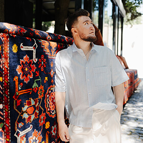 Portrait of a visitor beside a traditional Azerbaijani carpet display in the streets of Baku Old Town.