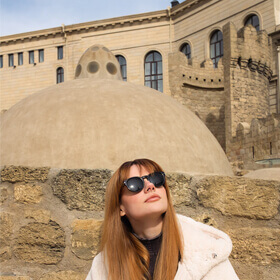 Женщина возле бани Хаджи Гаиб в Старом городе Баку с историческим куполом на фоне