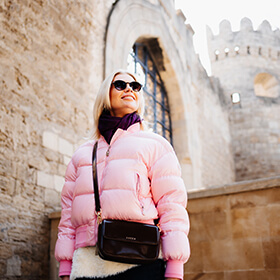 Женщина в розовой куртке у крепостных стен в Ичеришехер, Старый город Баку