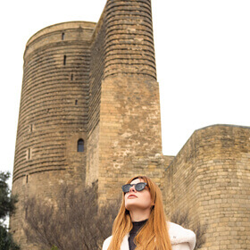Женщина на фоне Девичьей башни в Старом городе Баку во время фототура